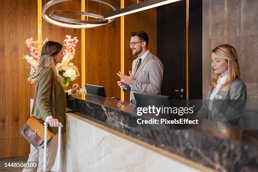 Male hotel receptionist assisting female guest Male hotel receptionist assisting female guest