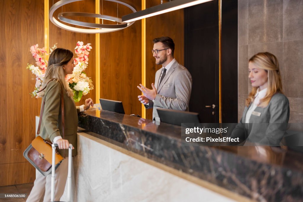 Male hotel receptionist assisting female guest