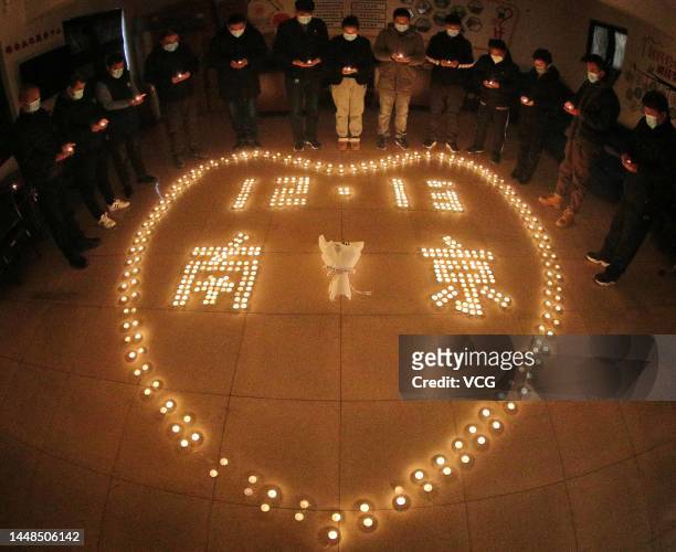 Residents circle around candles laid in the shape of a heart to mourn for victims of Nanjing Massacre ahead of China's National Memorial Day on...