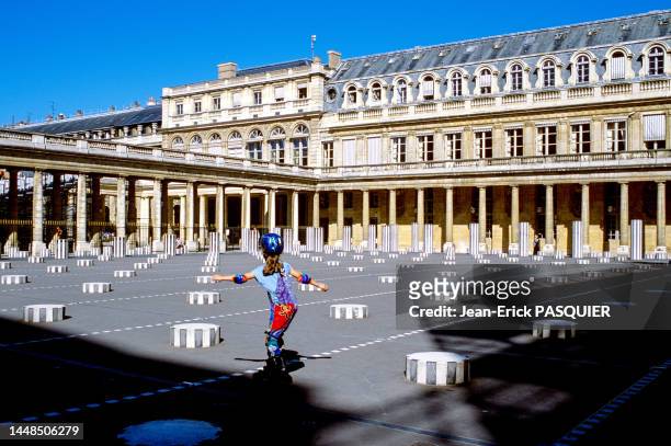 Fillette avec un casque et des protections aux genoux et coudes sur des rollers entre les colonnes de Buren dans les jardins du Palais Royal en 1986...