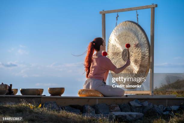 woman playing gong for sound therapy - gong stock pictures, royalty-free photos & images