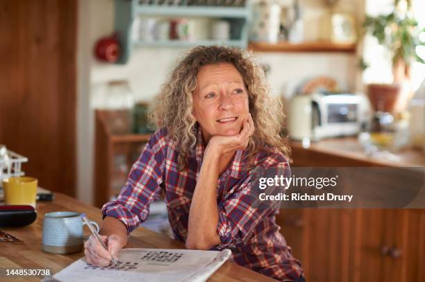 mature woman doing a crossword puzzle - crossword puzzle stock pictures, royalty-free photos & images