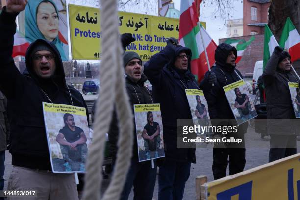 Protesters chant slogans next to a hangman's noose as they wear a photograph of Majid Reza Rahnavard during a demonstration by supporters of the...