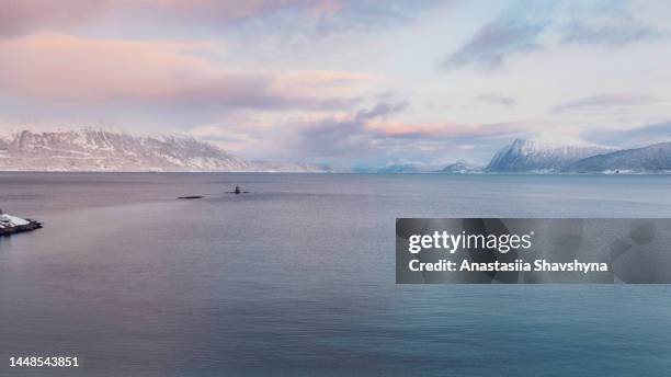 imagem aérea do mar turqouse cênico com montanhas nevadas no horizonte durante o dramático pôr do sol de inverno na noruega - mar da noruega - fotografias e filmes do acervo