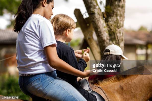 frau reitet auf einem pferd mit einem kleinen jungen - horse and male and riding stock-fotos und bilder
