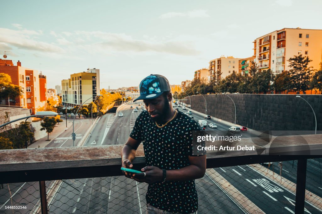Black African Man Using Technology Texting In A Bridge Over The Highway ...