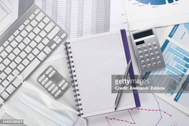 graphs and histograms, tablets, medical protective mask, medicine on the desktop. calculation of profit or loss due to price increases in the healthcare sector. the concept of the global crisis, economic problems in the medical industry, accounting report - tax scrutiny stock pictures, royalty-free photos & images