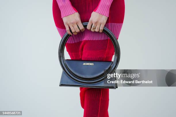 Close-up view of a pink and red ribbed see-through dress, a black leather bag from Jacquemus, outside the "Le Raphia" Jacquemus show on December 12,...