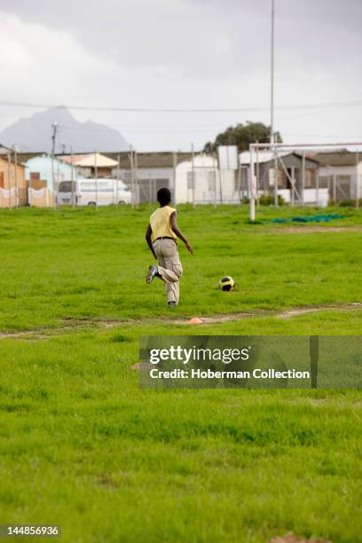 Boy kicking soccer ball in Township