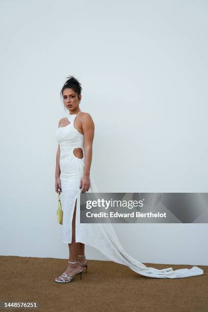 Adèle Exarchopoulos wears a white low neck long dress with side keyhole, a scarf, a yellow bag, white high heeled shoes, outside the "Le Raphia"...