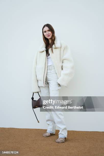 Pernille Teisbaek wears a white fluffy winter aviator jacket, a white t-shirt, white denim trousers, a brown leather bag, outside the "Le Raphia"...