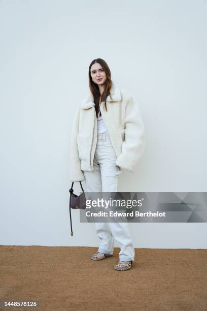 Pernille Teisbaek wears a white fluffy winter aviator jacket, a white t-shirt, white denim trousers, a brown leather bag, outside the "Le Raphia"...
