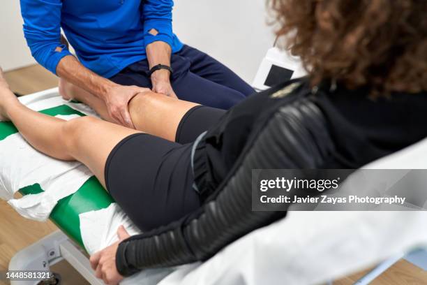 physiotherapist treating knee injury of a woman in  his rehabilitation clinic - knee surgery stock-fotos und bilder