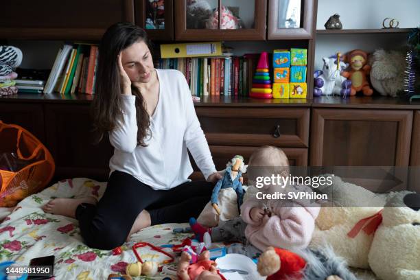 mother plays with her daughter with a headache. - tired mother stock pictures, royalty-free photos & images