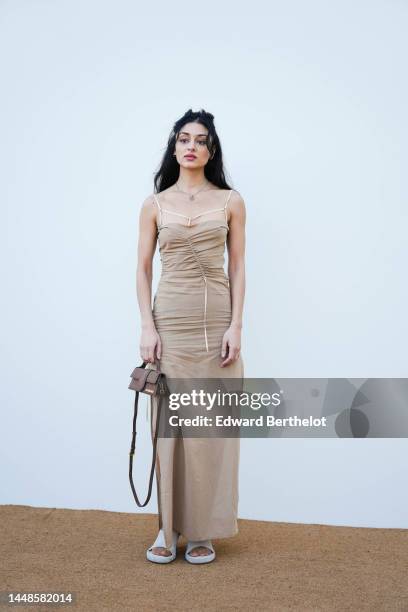 Sofie Royer wears a necklace, a beige off-shoulder gathered maxi dress, a brown Jacquemus bag, shoes, outside the "Le Raphia" Jacquemus show on...