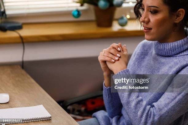 worried young woman sitting at her desk, stressing out while working during christmas holidays - knuckles stock pictures, royalty-free photos & images
