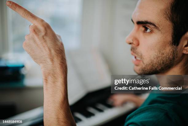 a young man points at something with conviction - bad singer stock pictures, royalty-free photos & images