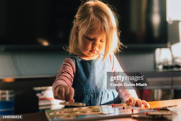 little girl playing with puzzles at home in backlight. - brain hand stock-fotos und bilder