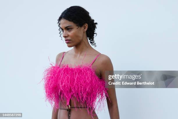 Tina Kunakey wears a neon pink fluffy cropped top / bras, a purple tight skirt with a lower fluffy part, outside the "Le Raphia" Jacquemus show on...