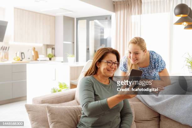 mãe e filha felizes fazendo uma chamada de vídeo com o telefone inteligente - mother daughter webcam - fotografias e filmes do acervo