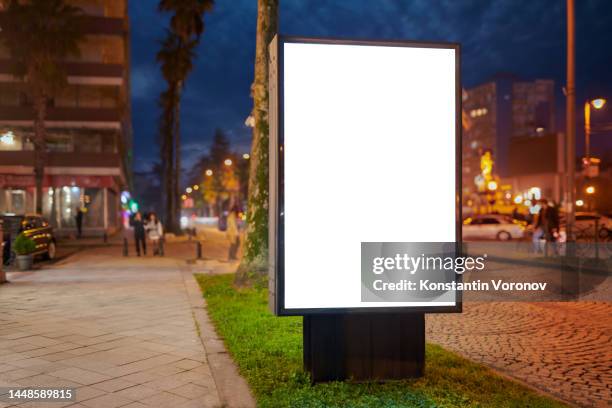 blank city format (lightposter, citylight) banner on the sidewalk in the night city street mockup.  pylon, a free-standing light box ready for your content - branded content stock pictures, royalty-free photos & images