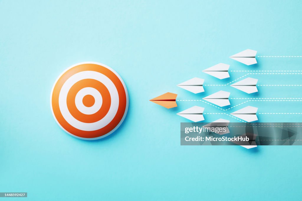 Papierflugzeuge bewegen sich auf ein orangefarbenes Bullauge-Ziel auf blauem Hintergrund zu