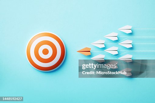 Papierflugzeuge bewegen sich auf ein orangefarbenes Bullauge-Ziel auf blauem Hintergrund zu Papierflugzeuge bewegen sich auf ein orangefarbenes Bullauge-Ziel auf blauem Hintergrund zu