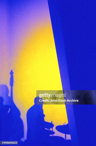 View the shadows of a Jazz musicians, one on upright double bass and the other on drums, as they perform onstage, New York, New York, 1983.