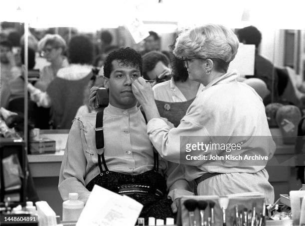Puerto Rican Rock musician Carlos Alomar sits in a makeup chair as a woman applies his eyeliner backstage, before an appearance on Saturday Night...