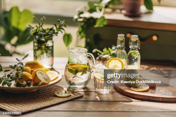 lemonade in glass jug on wooden table outdoors. summer refreshing drink. cold detox water with lemon - alcohol detox foto e immagini stock