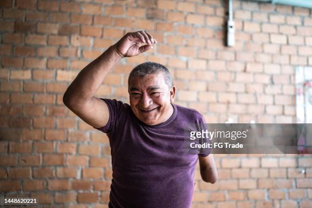 mature man with partial arm amputation dancing on a dance class - disabilitycollection stock pictures, royalty-free photos & images