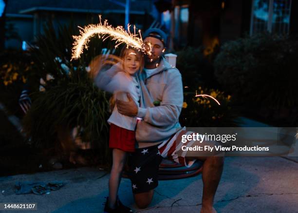 dad and daughter celebrating the fourth of july with fireworks - brilhante fogo de artifício imagens e fotografias de stock