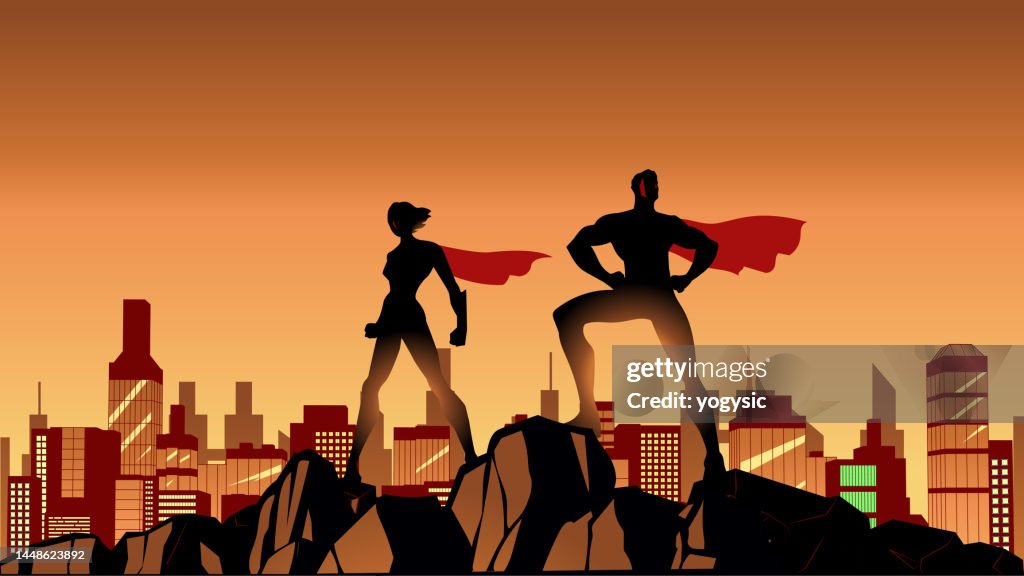 Vector Superhero Couple Silhouette Standing on a Cliff with Cityscape Background Stock Illustration
