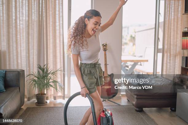 cleaning, vacuum and sing with a black woman doing housework in her home living room alone. happy, housekeeping and carefree with a female cleaner signing while in her house to clean for chores - vacuum cleaner woman stockfoto's en -beelden