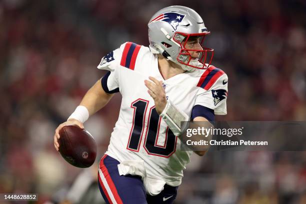 Mac Jones of the New England Patriots scrambles with the ball against the Arizona Cardinals during the first quarter of the game at State Farm...