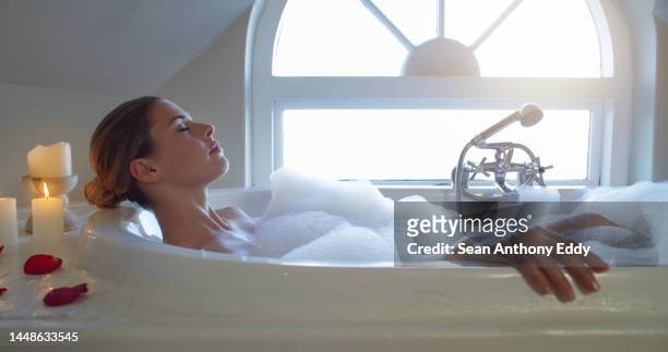 self care with candles, luxury in rose bath water with bubble and wellness spa for calm woman in the bathroom at home. sleeping, relax and skincare for body health for young girl in hotel bathtub - woman bath bubbles stock pictures, royalty-free photos & images