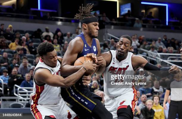 Kyle Lowry and Bam Adebayo of the Miami Heat batlte for a loose ball with Myles Turner of the Indiana Pacers at Gainbridge Fieldhouse on December 12,...