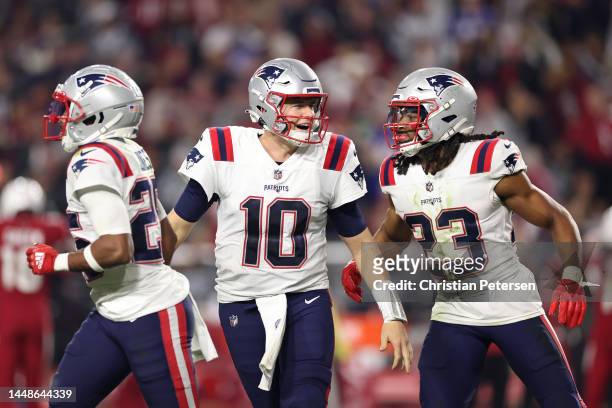Mac Jones of the New England Patriots celebrates with Marcus Jones and Kyle Dugger after a defensive stop against the Arizona Cardinals during the...