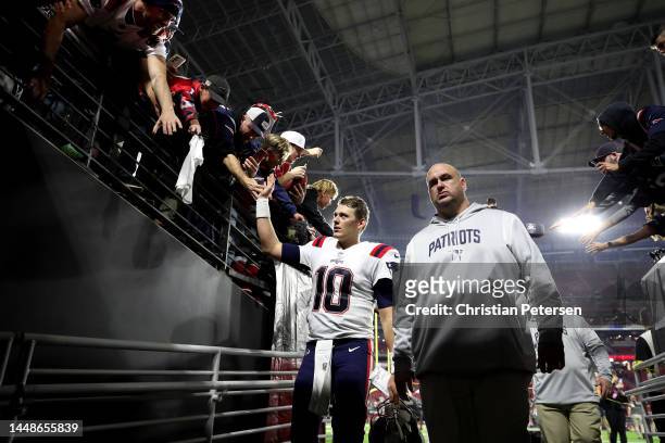 Mac Jones of the New England Patriots high-fives fans as he leaves the field after defeating the Arizona Cardinals in the game at State Farm Stadium...