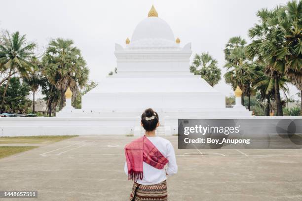 rear view of asian woman standing in front of an iconic 'watermelon' stupa in wat wisunalat temple in luang prabang, laos. - vat fotografías e imágenes de stock