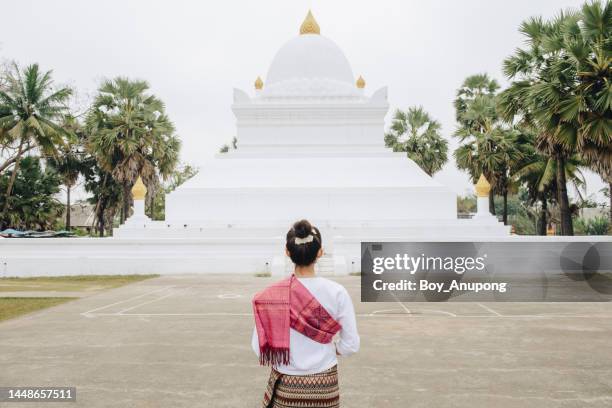 rear view of asian woman standing in front of an iconic 'watermelon' stupa in wat wisunalat temple in luang prabang, laos. - wat imagens e fotografias de stock