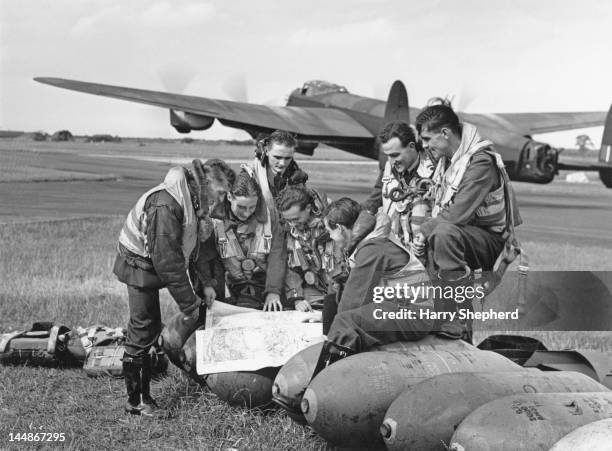 The crew of an RAF Lancaster bomber discuss their flight before take-off from an airfield in East Anglia, 15th September 1944. They are preparing to...