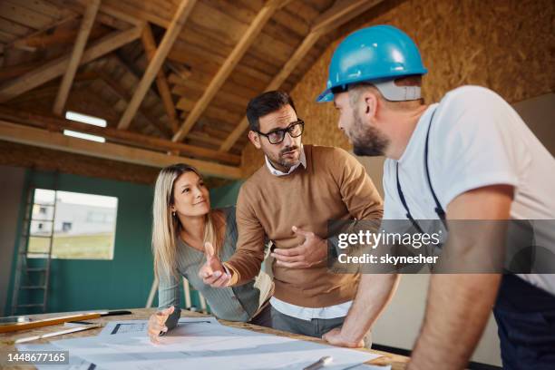 pareja joven hablando sobre diseño de viviendas con trabajador manual. - building contractor fotografías e imágenes de stock