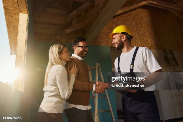 la feliz pareja llegó a un acuerdo con el trabajador manual en el sitio de construcción. - contratista de obras fotografías e imágenes de stock