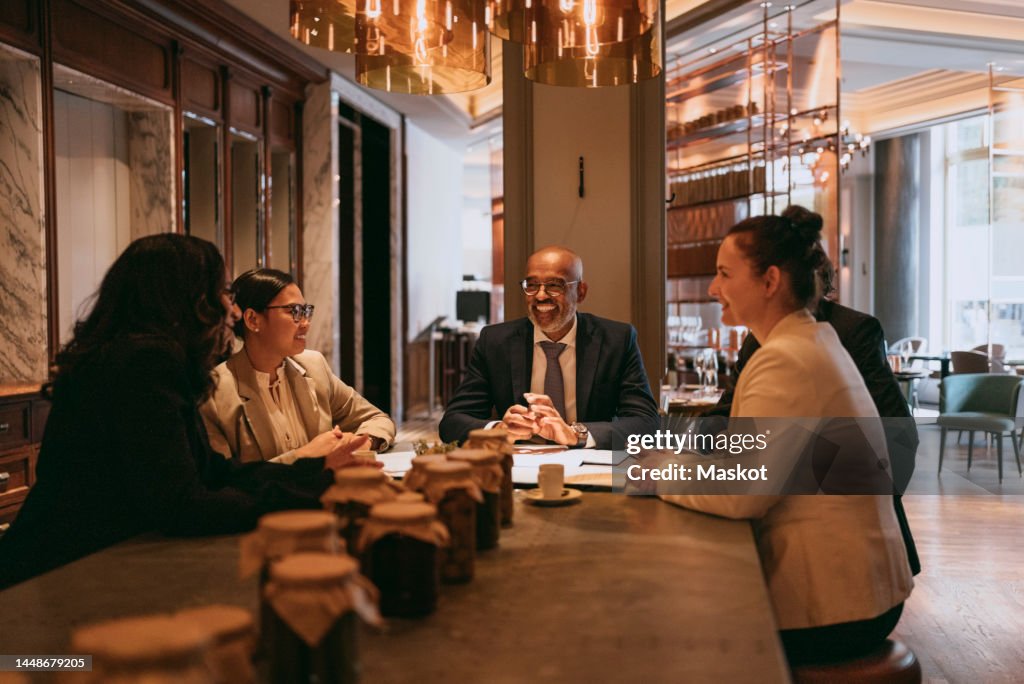 Smiling multiracial colleagues at dining table during lunch meeting in restaurant