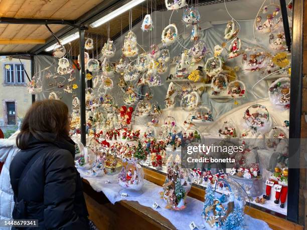 frau schaut auf einen weihnachtsmarktstand in einer innenstadt - frankreich souvenir reise stock-fotos und bilder