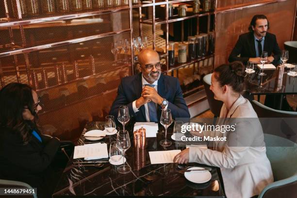 smiling business colleagues discussing at table during meeting in restaurant - business lunch stock-fotos und bilder