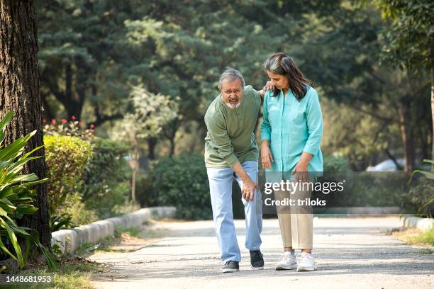 senior man is having knee pain in the park - knie stockfoto's en -beelden