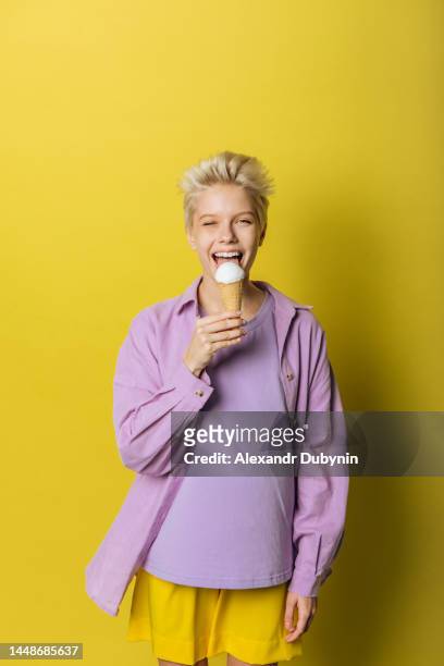 young woman teenager with positive emotions with ice cream on yellow background studio shot - food studio shot stock pictures, royalty-free photos & images