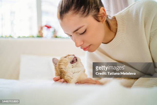 bound and trust between pet and owner. blond woman lying face to face with domestic cat with open mouth in white bed - meowing bildbanksfoton och bilder